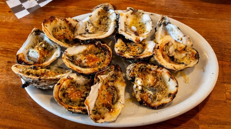 Chargrilled oysters with herbs on a white plate