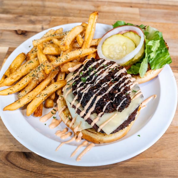 Bacon jam burger with cheese, sauce drizzle, and seasoned fries