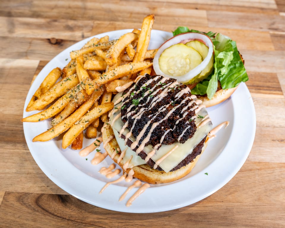 Bacon jam burger with cheese, sauce drizzle, and seasoned fries