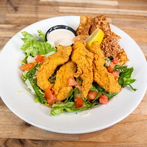 Chicken finger salad with crispy wontons, tomatoes, and ranch dressing