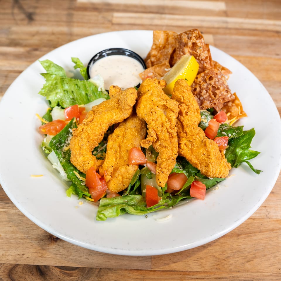 Chicken finger salad with crispy wontons, tomatoes, and ranch dressing
