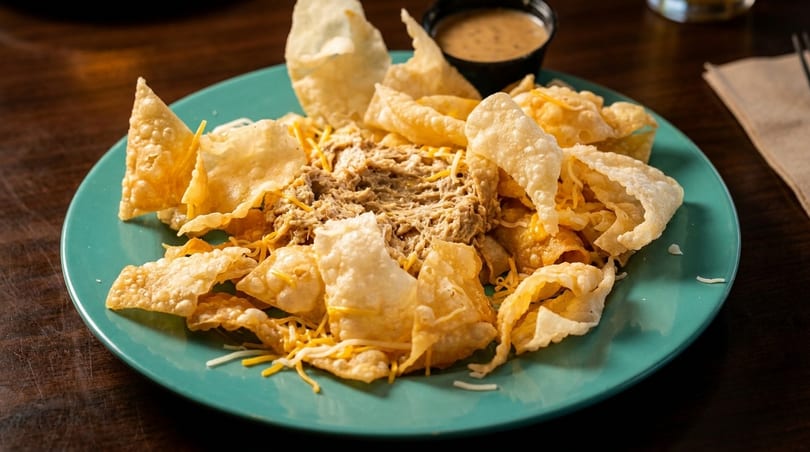 Tuna dip with crispy fried wontons and shredded cheese on a teal plate