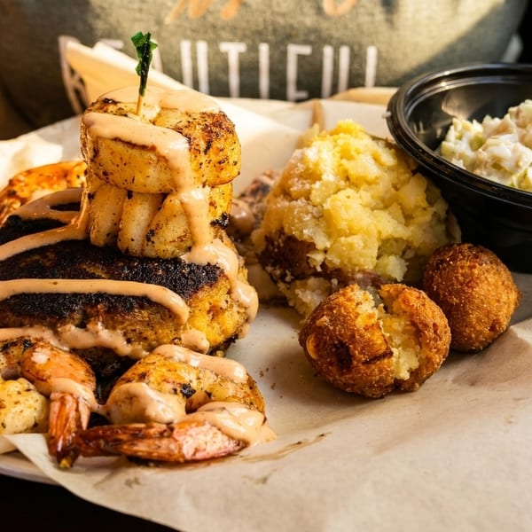 Lunch stack with blackened fish, grilled shrimp, and hushpuppies with coleslaw